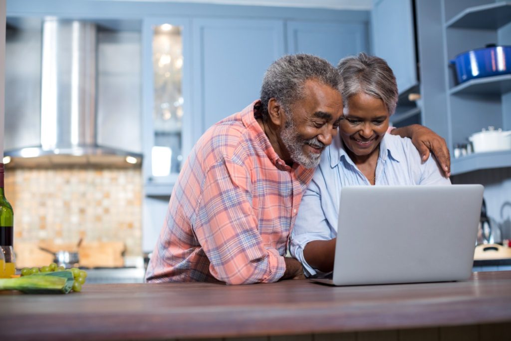Smiling Couple Using Laptop Computer to research medicare supplement insurance